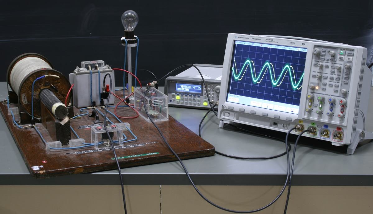 Same LRC setup from slightly different angle, oscilloscope showing two phase-shifted sinusoidal traces