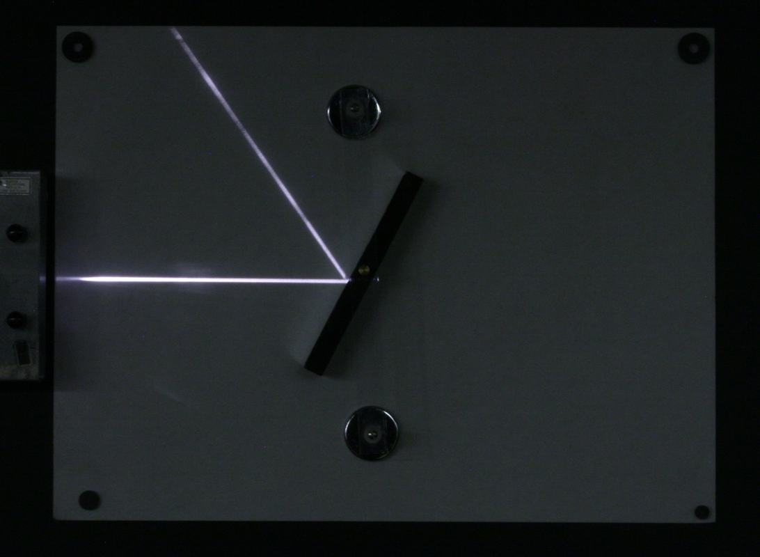 White optics board with ray projector at left edge projecting a single ray that reflects off a black plane mirror mounted magnetically on the board