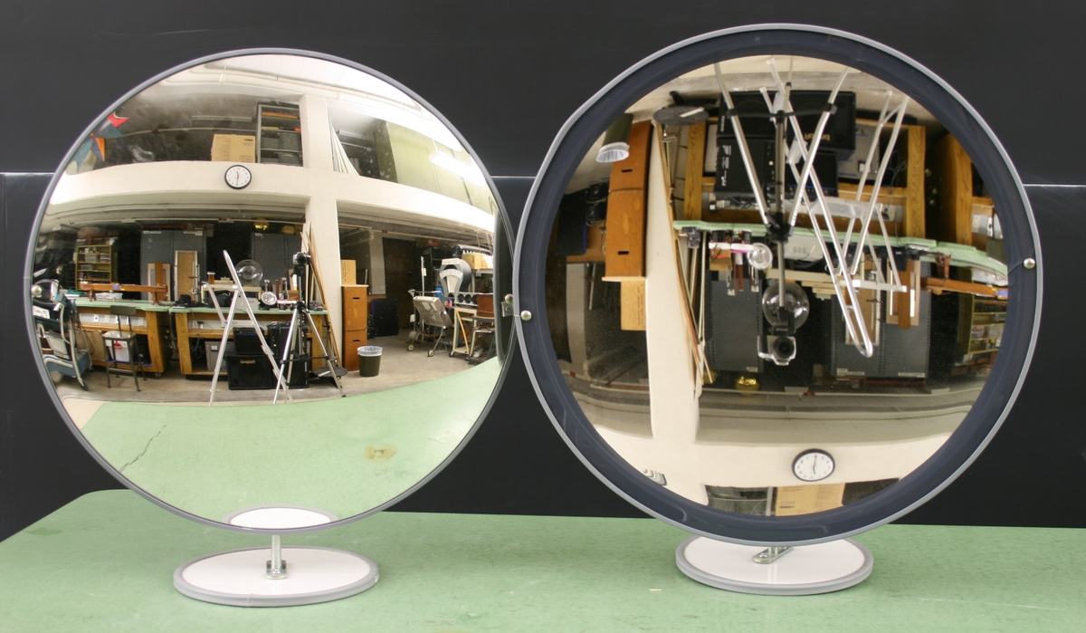 Two large 60cm circular mirrors on pedestal stands: left mirror (concave) shows an inverted reflection of the room, right mirror (convex) shows an upright but diminished reflection