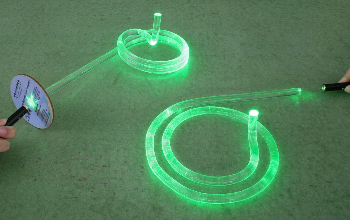 Both Lumirods glowing green as light from fiber optic sources travels through the curved acrylic paths