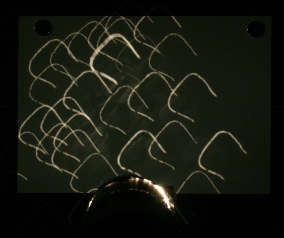 Dark screen showing many separate bright filament images scattered across the surface, with the lamp visible at the bottom edge