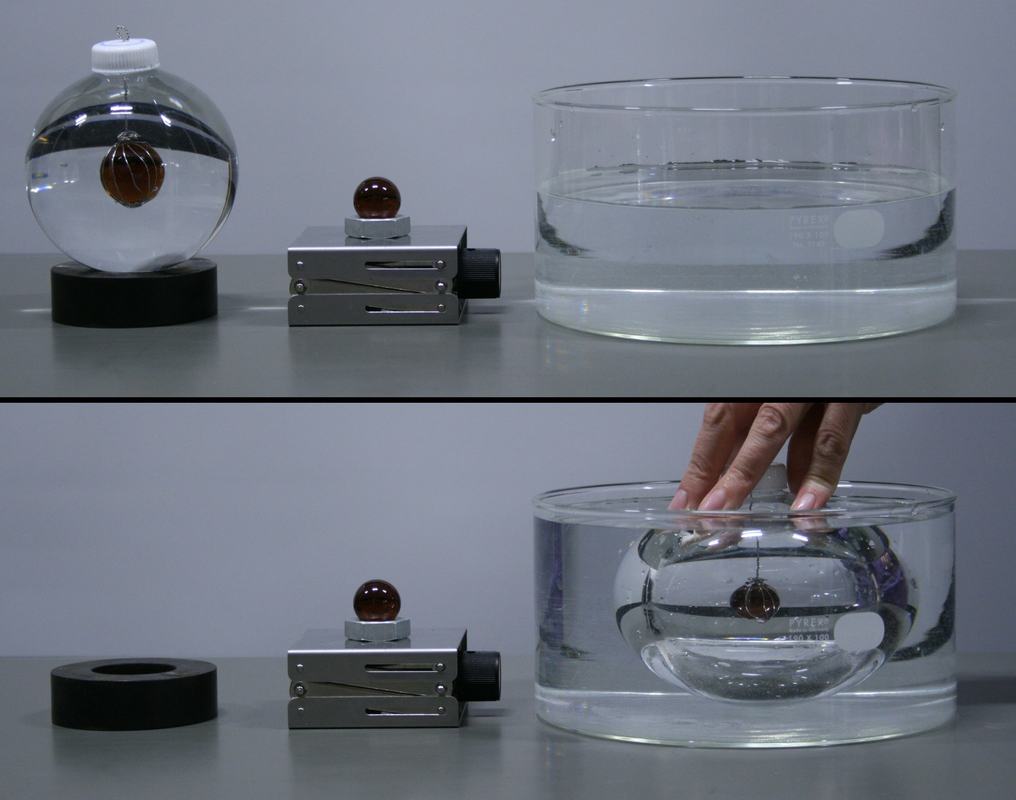 Two-panel image. Top: water-filled spherical globe on rubber ring with magnified marble visible inside, reference marble on lab jack, empty cylindrical glass dish. Bottom: globe submerged in water-filled dish with hand pushing it down, marble appears smaller.
