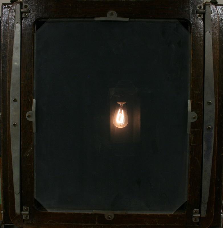 Close-up of ground glass screen showing inverted real image of the carbon filament lamp bulb