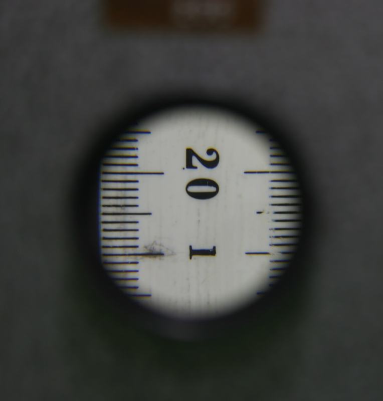 Camera view through the microscope model showing magnified ruler markings around 19-21 cm with visible graduation lines