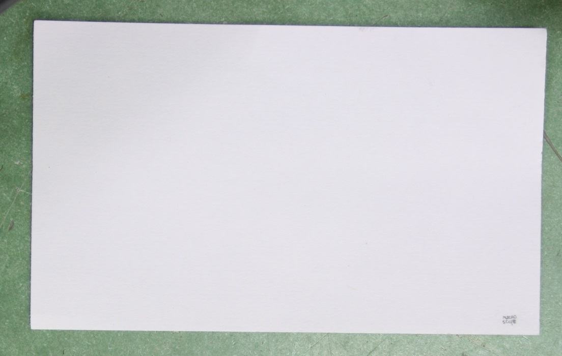 White index card on green bench surface with the word "microscope" written small in the bottom right corner