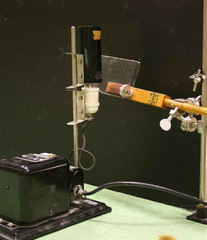 Mercury lamp with slit aperture on vertical stand, transformer box at base, and mica sheet held at angle by wooden clamp arm on ring stand