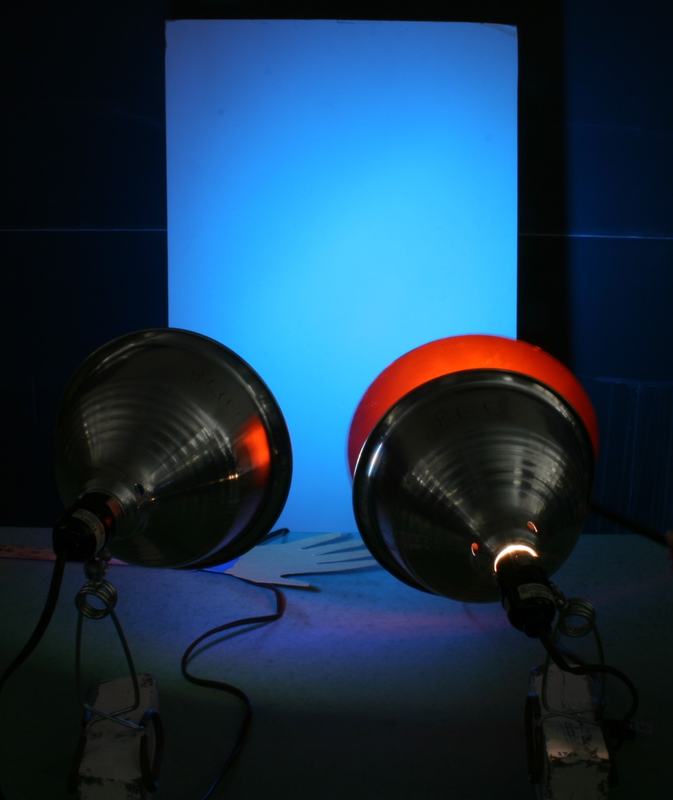 Screen illuminated in bright blue with both flood lamps visible; only the blue lamp is on
