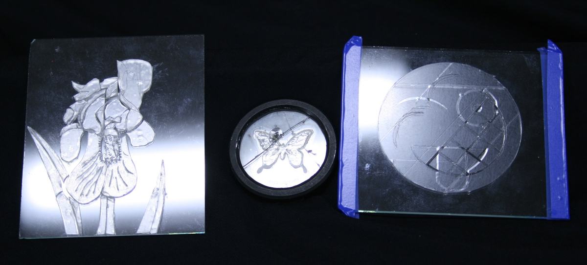 Three birefringent image plates: square iris plate on left, circular butterfly mount in center, rectangular emoji face plate with blue tape edges on right