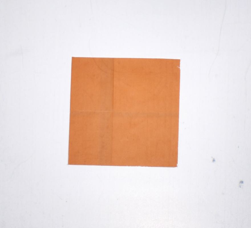 Same orange origami paper square on white background, appearing more brown or muted