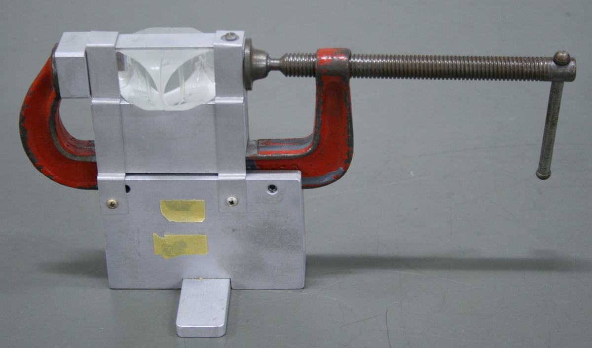 Close-up of the clamped prisms apparatus: two right-angle prisms in an aluminum housing with a red C-clamp for adjusting the gap between hypotenuse faces