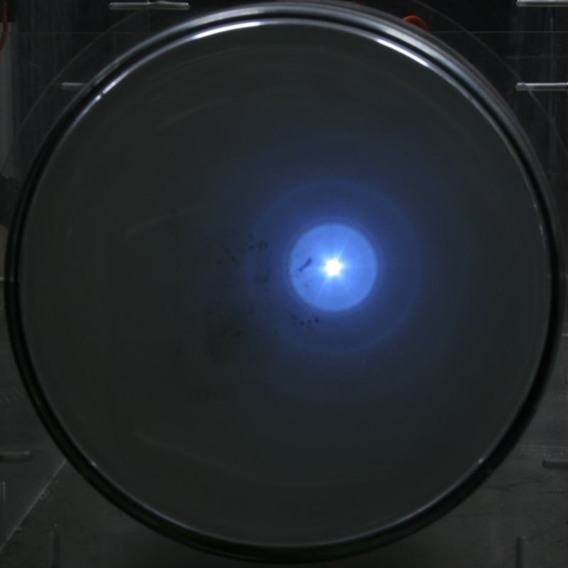 Phosphorescent screen with tightly focused bright central spot and close-in diffraction ring at higher voltage