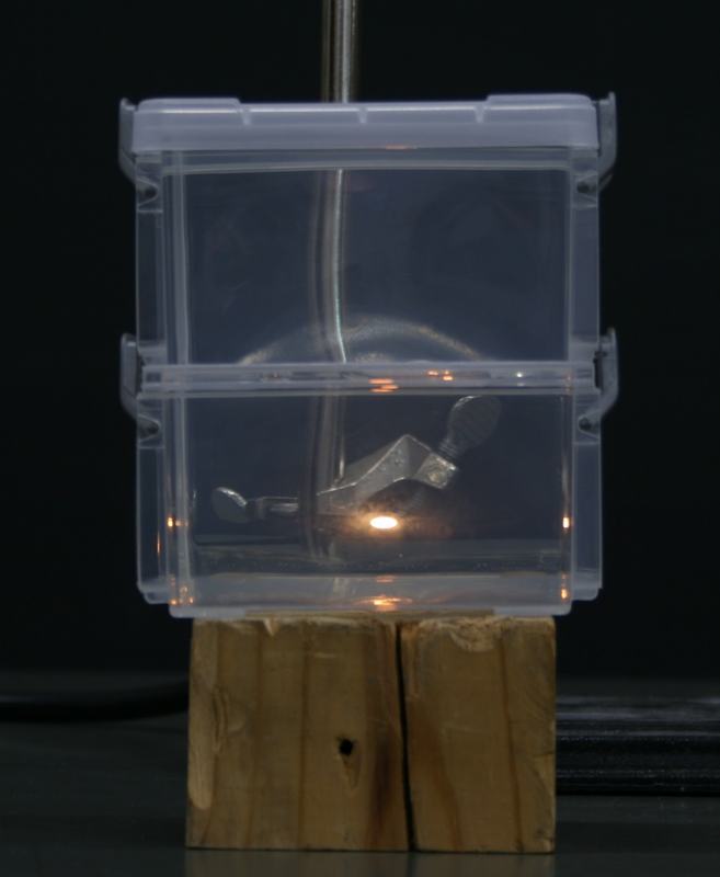 Stacked containers with light source deeper in the lower container, appearing strongly flattened into a horizontal ellipse
