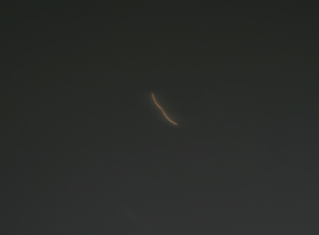 Glowing filament projected on screen against a dark background, appearing as a faint bright curved line