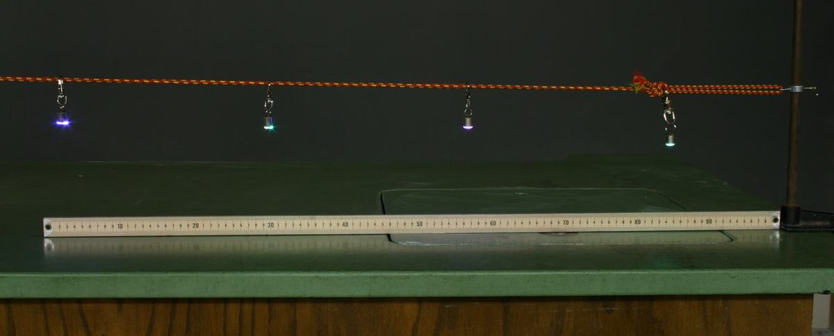 Same four LEDs on the now-stretched orange bungee cord, showing increased spacing between all LEDs compared to the initial configuration