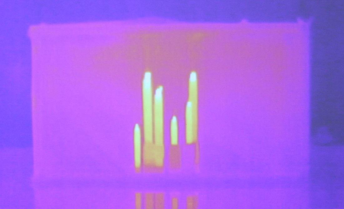 Infrared thermal image showing a hand's warm fingers (bright yellow-white) against a cooler purple-pink background